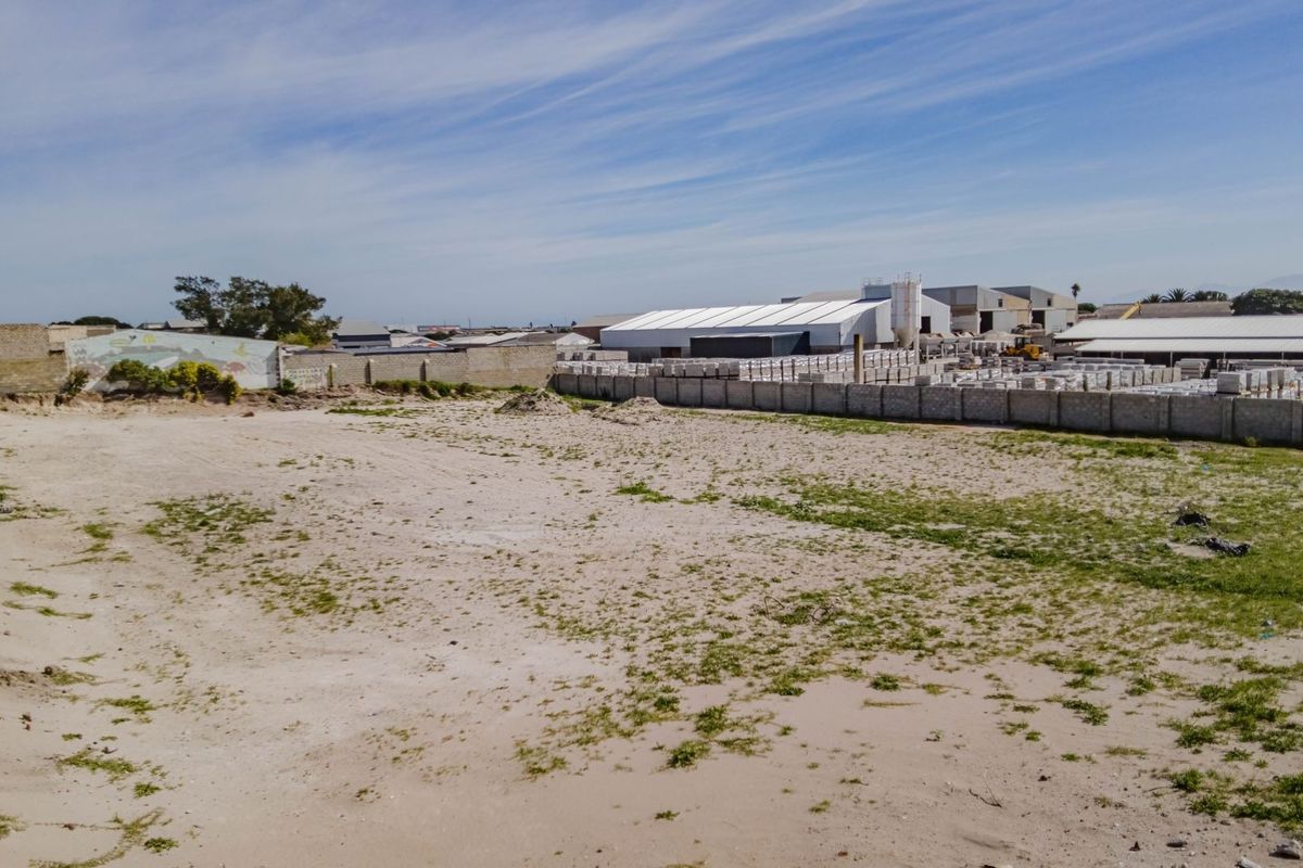 A vacant commercial land plot featuring perimeter walling and boundary fencing, situated in an established industrial or commercial area.