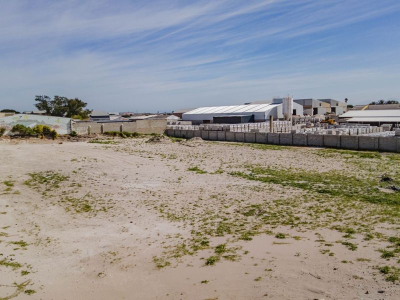 A vacant commercial land plot featuring perimeter walling and boundary fencing, situated in an established industrial or commercial area.