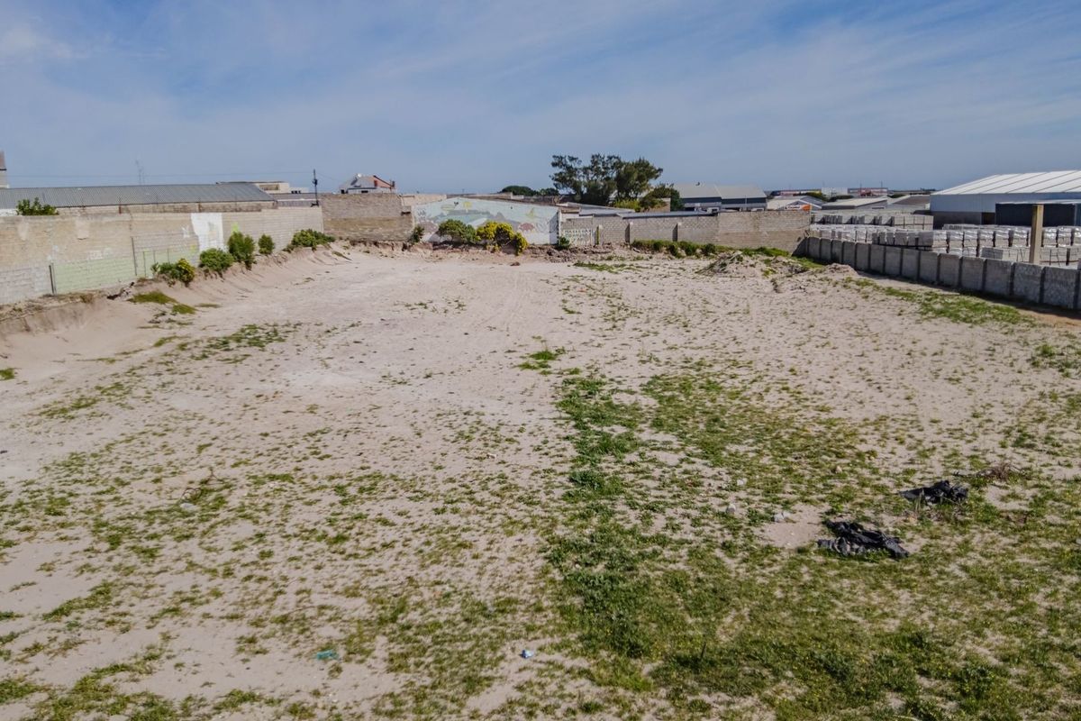 An elevated view of a vacant commercial plot featuring a sandy surface and enclosed by perimeter boundary walls.