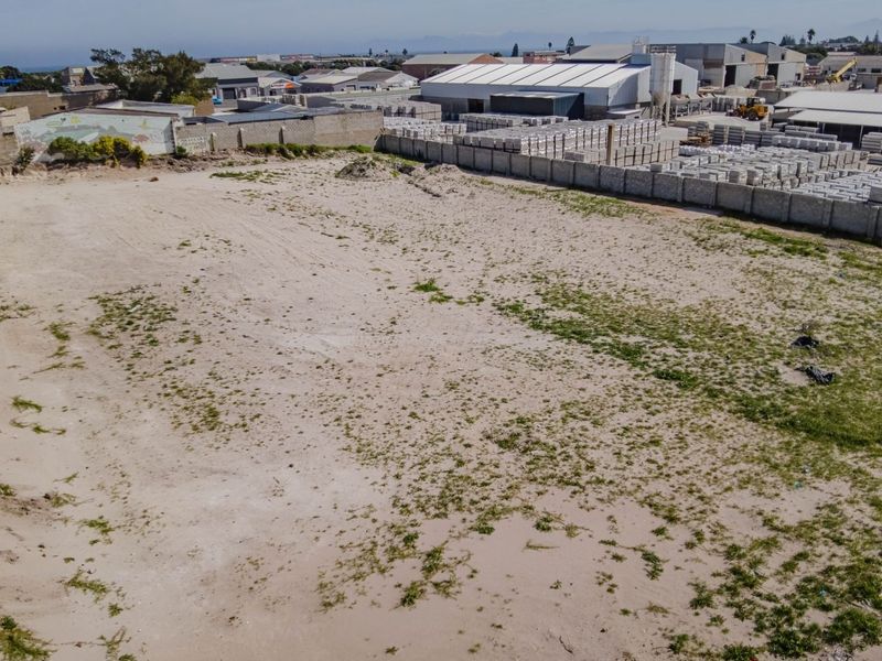 Aerial view of a vacant commercial land plot featuring perimeter boundary walls and level ground, situated in an industrial area.