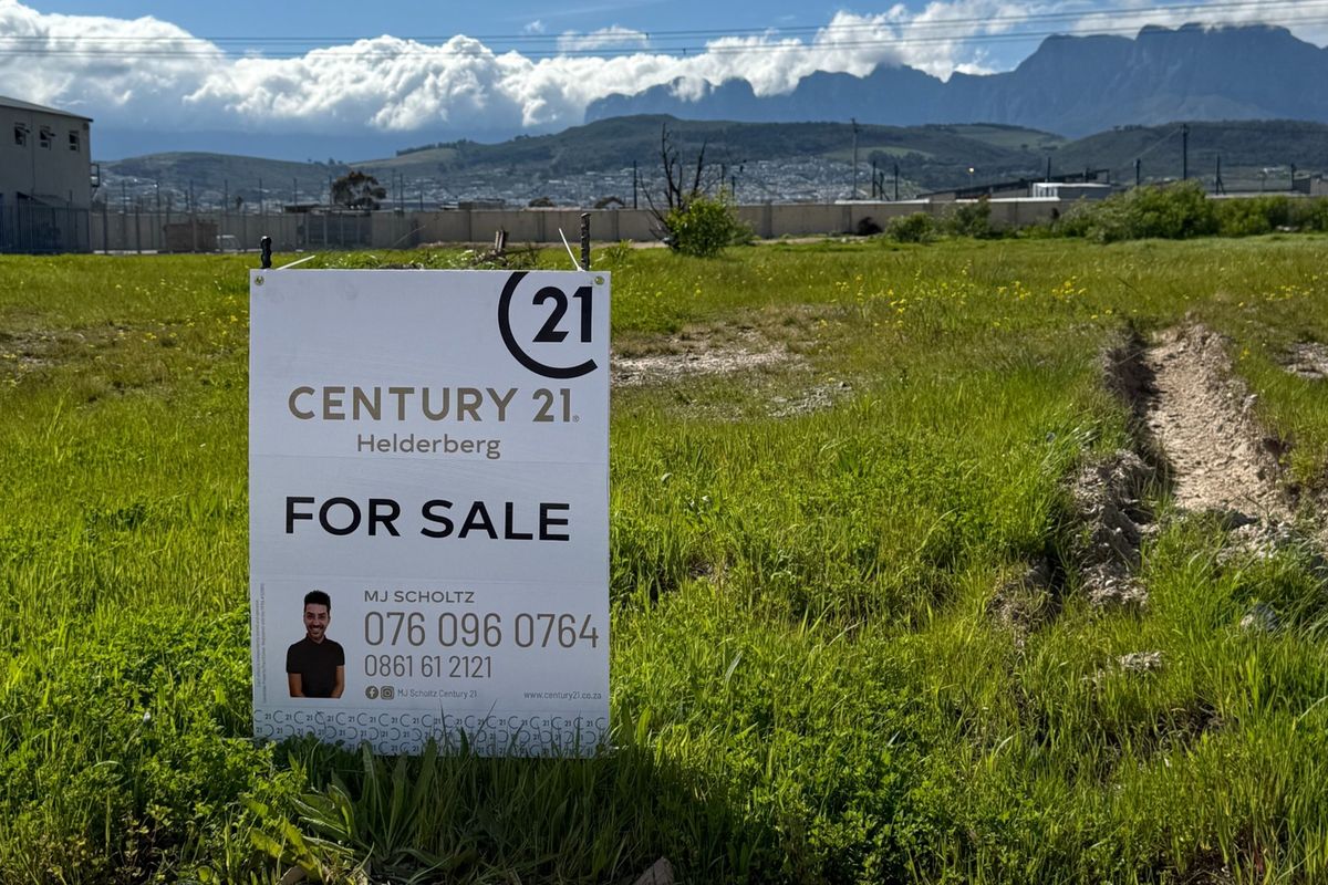 A vacant commercial land plot featuring mountain views and perimeter fencing, currently available for development.