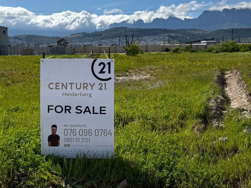 A vacant commercial land plot featuring mountain views and perimeter fencing, currently available for development.