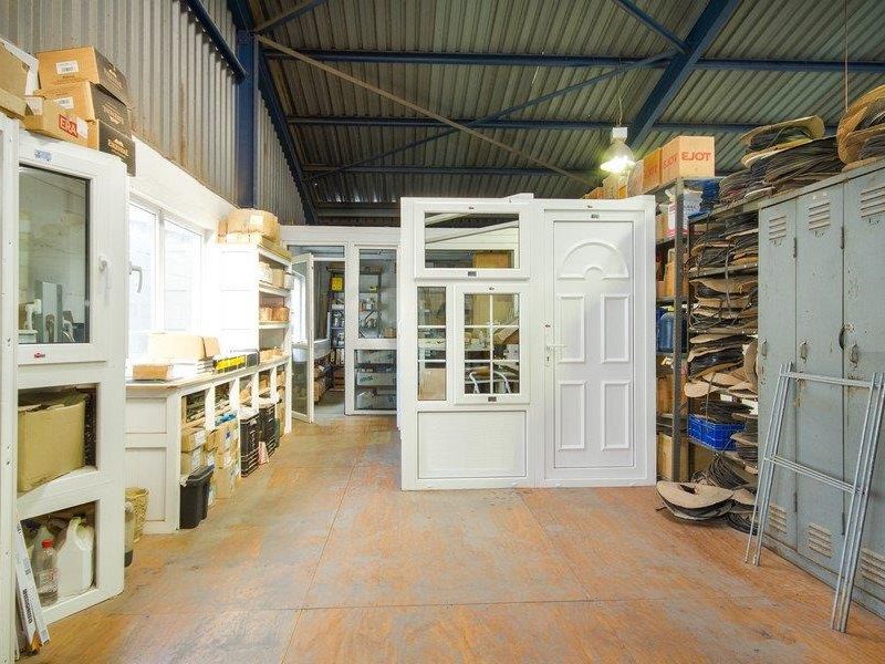 Industrial utility space featuring exposed steel roof trusses, corrugated metal walls, and extensive built-in metal shelving and storage lockers.