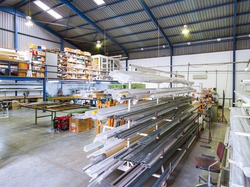 Spacious industrial warehouse featuring a mezzanine level, high exposed steel roof trusses, and durable concrete flooring, suitable for manufacturing or storage operations.