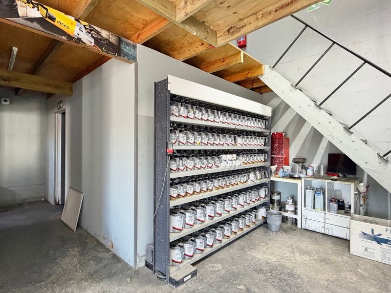 Industrial utility space featuring exposed timber ceiling joists, a metal staircase, and integrated industrial shelving for storage.