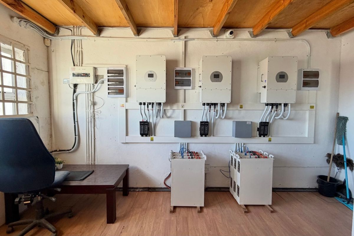 Utility room featuring a professional solar power installation with multiple inverters, battery storage units, and organized electrical distribution boards.