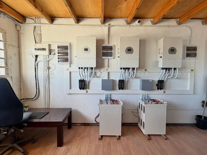 Utility room featuring a professional solar power installation with multiple inverters, battery storage units, and organized electrical distribution boards.