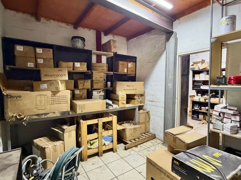Industrial utility or storage space featuring built-in shelving, exposed steel structural beams, and timber ceiling rafters with tiled flooring.