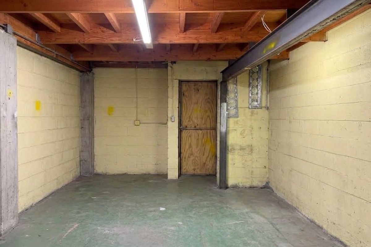 An empty industrial utility space featuring exposed timber ceiling beams, concrete block walls, and a durable concrete floor.