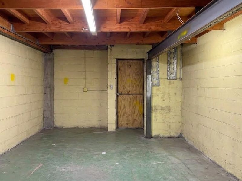 An empty industrial utility space featuring exposed timber ceiling beams, concrete block walls, and a durable concrete floor.