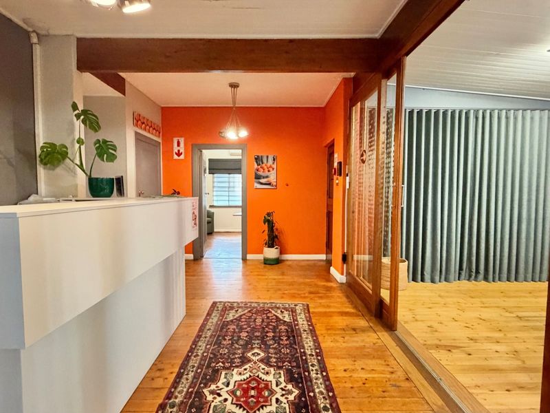 A welcoming reception area featuring timber flooring, a built-in desk, and a sliding glass door leading to an adjacent space.