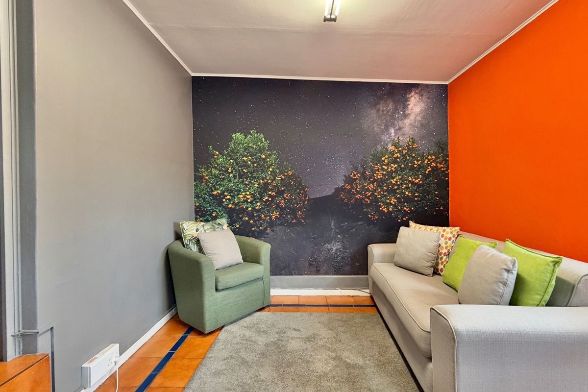 A living area featuring tiled flooring and a bold accent wall with a mural, providing a distinct space for relaxation.