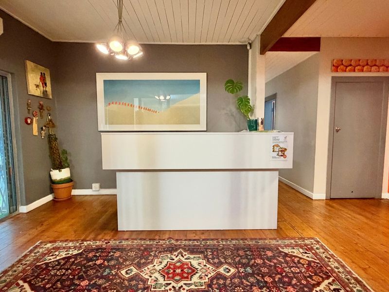 A welcoming reception area featuring polished timber flooring, a built-in reception desk, and a timber-paneled ceiling with integrated lighting.