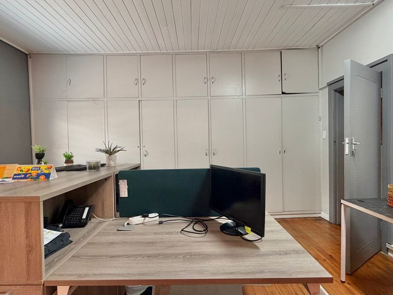 Functional office space featuring extensive built-in storage cabinetry, timber flooring, and a classic tongue and groove ceiling finish.