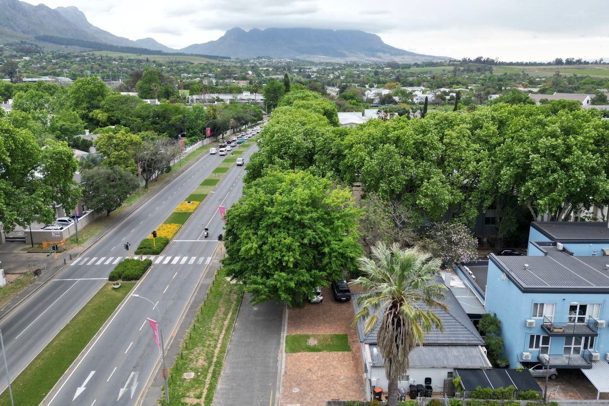 Aerial view of the property showing the surrounding street infrastructure, mature trees, and mountain backdrop.