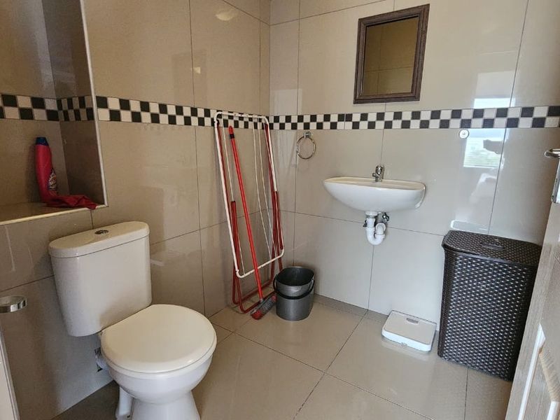 A functional bathroom featuring tiled walls with a decorative border, a wall-mounted basin, and a standard toilet.