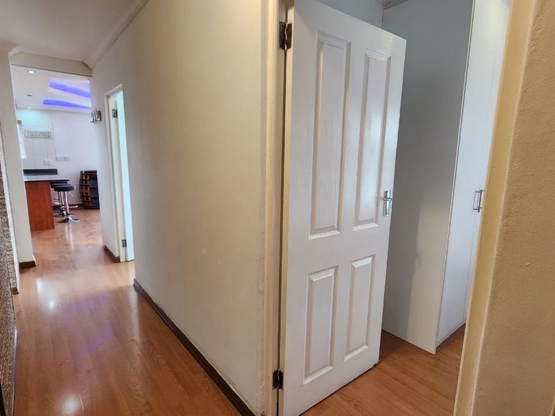 A bright hallway featuring laminate flooring, built-in storage cupboards, and access to adjacent living areas.