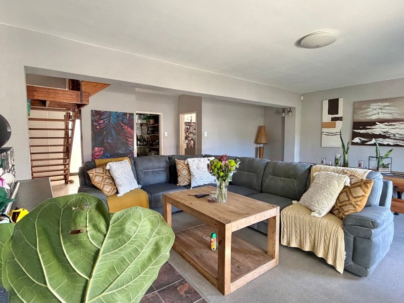 Spacious living room featuring a wooden staircase, tiled hearth, and neutral wall finishes, offering a comfortable and functional layout for relaxation.