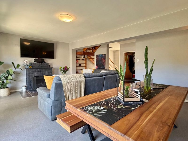 Open-plan living and dining area featuring a brick fireplace, staircase, and sliding glass doors leading to the exterior.