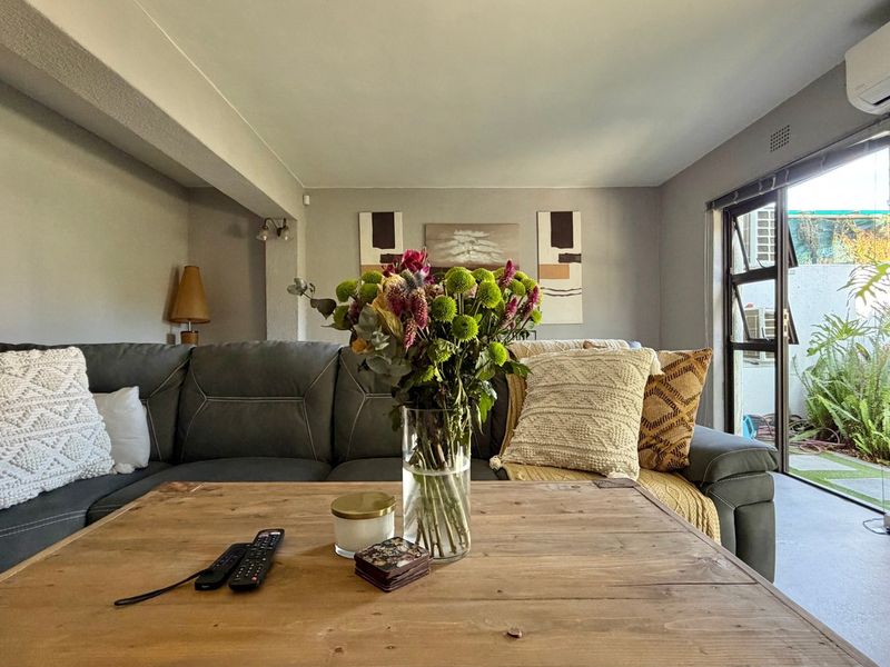 A comfortable living room featuring tiled flooring, an air conditioning unit, and a large sliding glass door providing access to the outdoor area.