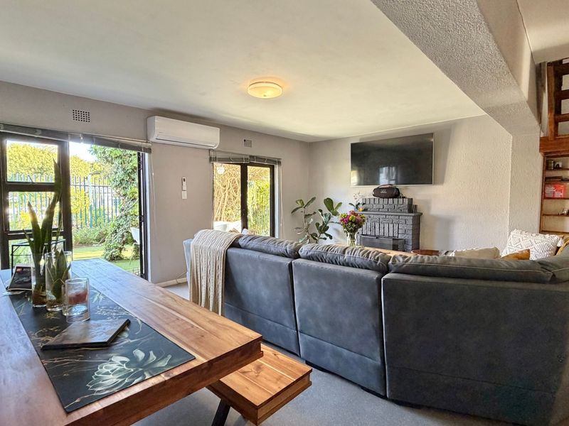 Open-plan living and dining area featuring a brick fireplace, split-system air conditioning, and direct access to the garden through sliding glass doors.