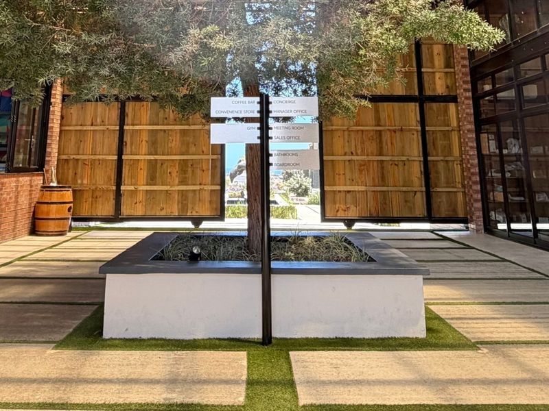 A well-maintained outdoor courtyard area featuring a central planter box, paved walkways, and large wooden sliding doors leading into the building.
