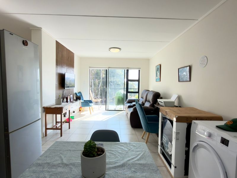 Open-plan living area featuring tiled flooring, a wood-look feature wall, and sliding glass doors leading to an outdoor space.