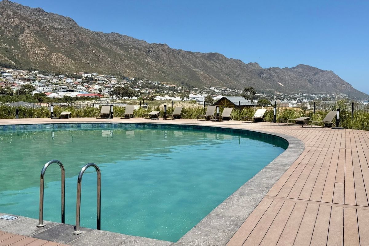 A well-maintained swimming pool area featuring composite decking, a pool ladder, and scenic mountain views in a tranquil outdoor setting.