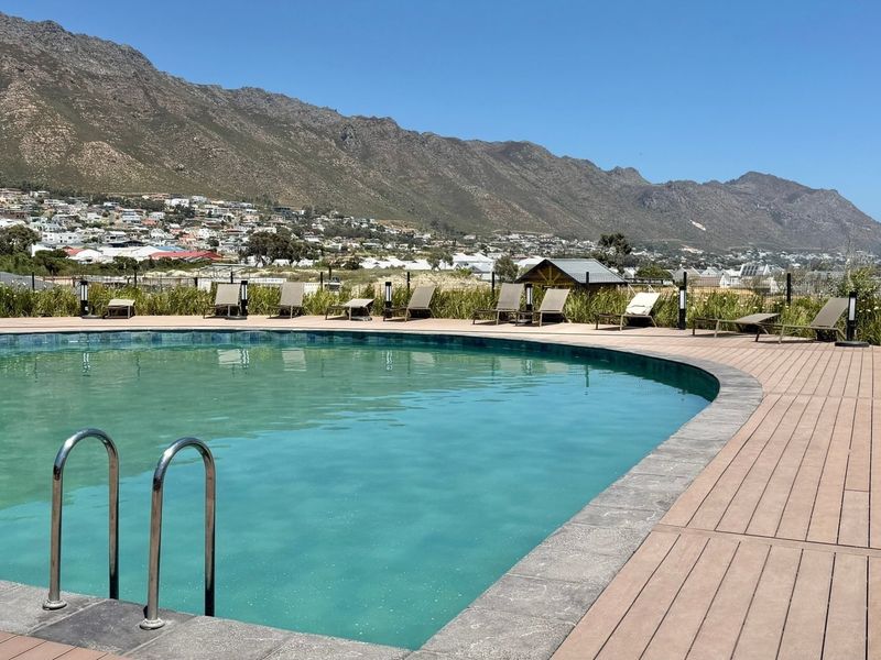 A well-maintained swimming pool area featuring composite decking, a pool ladder, and scenic mountain views in a tranquil outdoor setting.