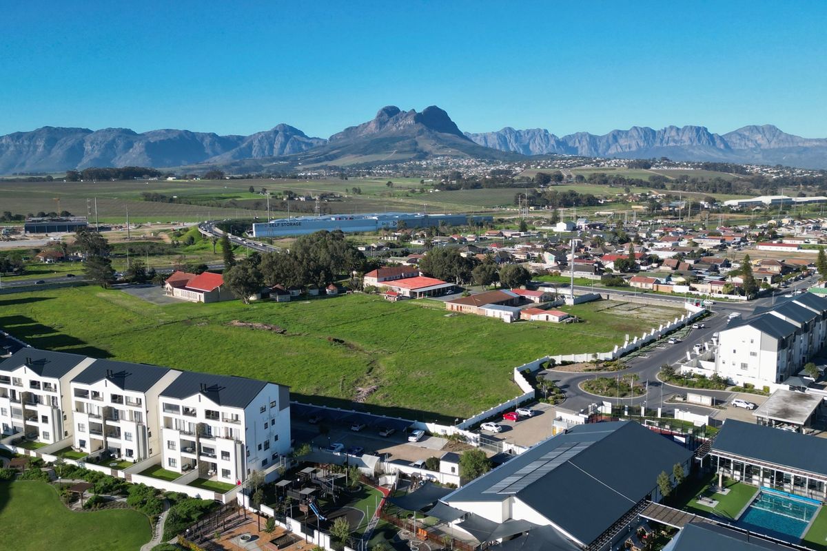Aerial view of the apartment complex featuring a swimming pool, landscaped grounds, and surrounding residential neighborhood with mountain views.