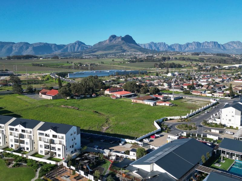 Aerial view of the apartment complex featuring a swimming pool, landscaped grounds, and surrounding residential neighborhood with mountain views.