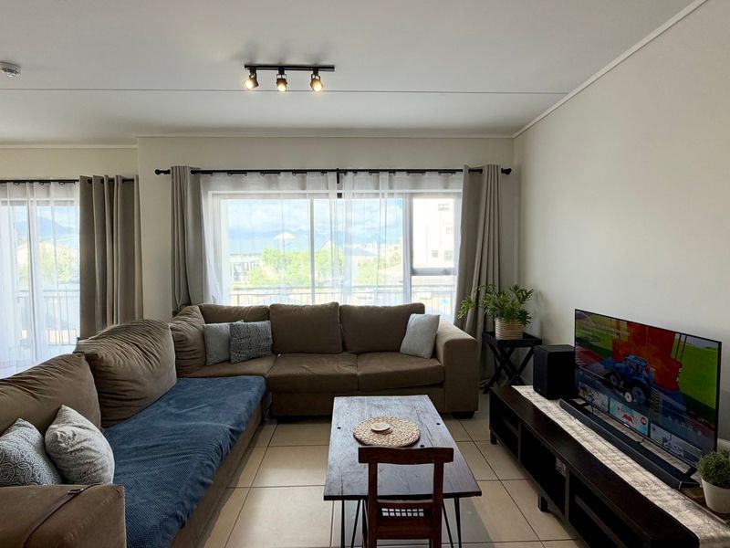 A bright and spacious living room featuring large sliding glass doors that provide natural light and access to the balcony.