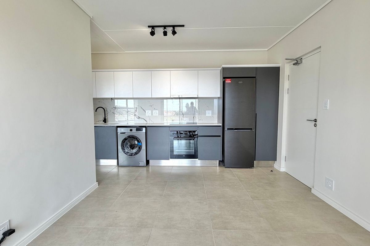 Modern kitchen featuring sleek two-tone cabinetry, marble-look splashback, integrated oven, and tiled flooring in an open-plan layout.