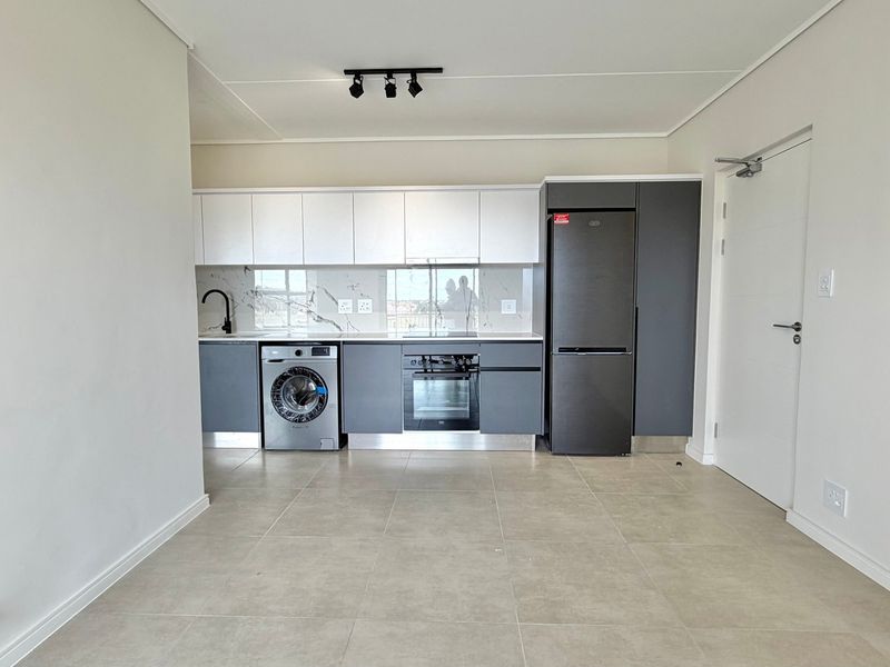 Modern kitchen featuring sleek two-tone cabinetry, marble-look splashback, integrated oven, and tiled flooring in an open-plan layout.