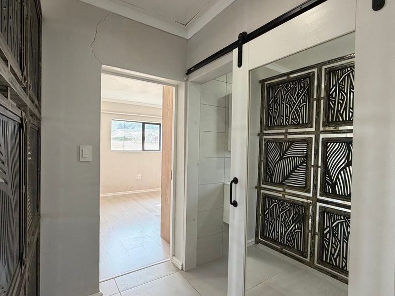A hallway featuring tiled flooring and a sliding barn door, with a view into an adjacent room.