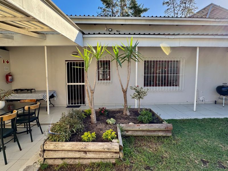 A covered patio area featuring tiled flooring, security fixtures, and a raised timber garden bed, providing a functional outdoor space for relaxation.
