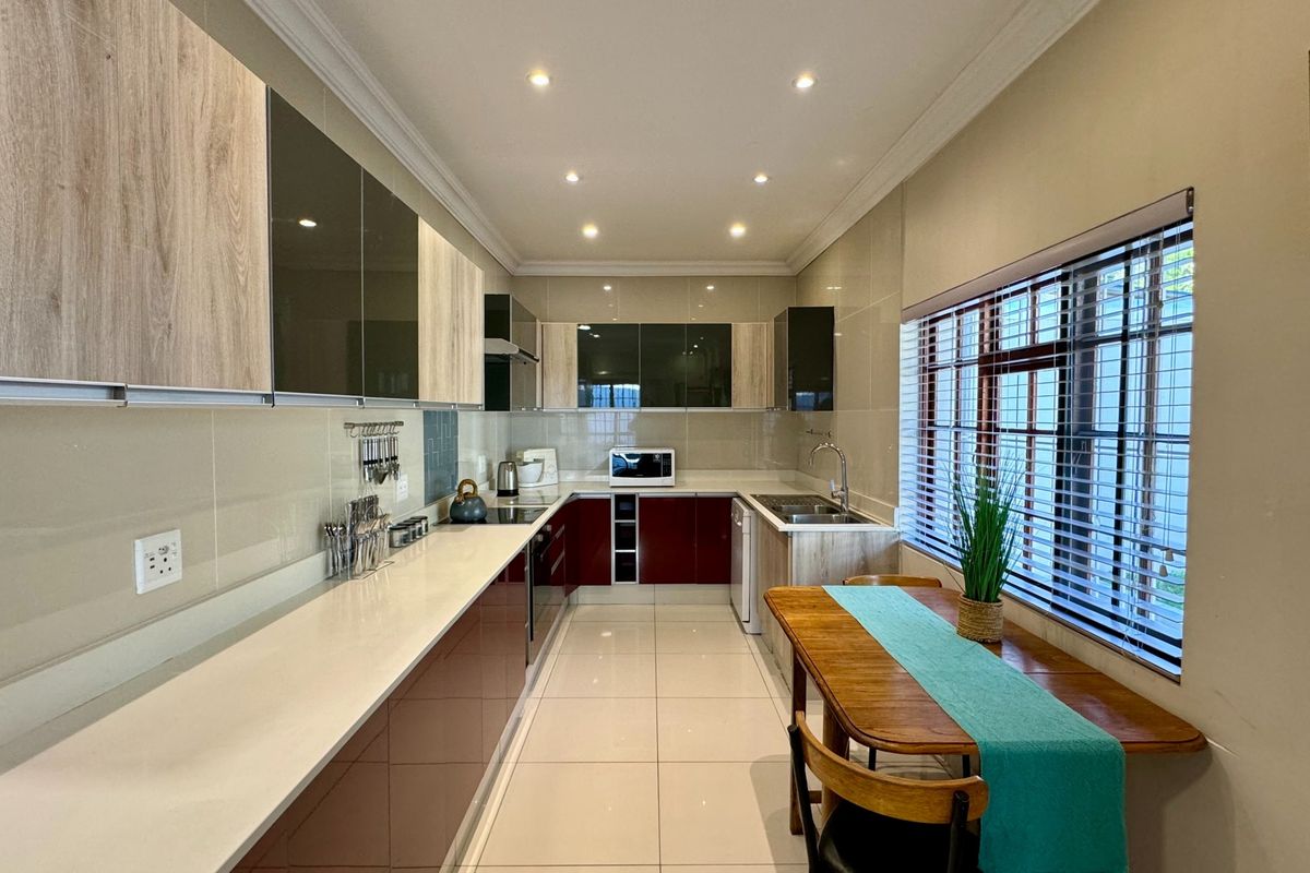 Modern galley-style kitchen featuring sleek two-tone cabinetry, stone countertops, tiled flooring, and recessed lighting, offering a clean and functional workspace.
