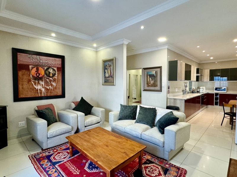 Spacious open-plan living area featuring a modern kitchen with stone countertops, sleek cabinetry, and a cozy freestanding fireplace, finished with polished porcelain floor tiles.