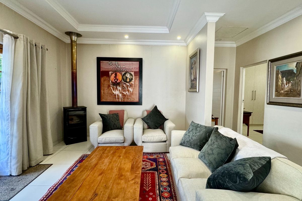 A well-maintained living room featuring tiled floors, crown molding, recessed lighting, and a cozy freestanding fireplace with direct access to the outdoor area.