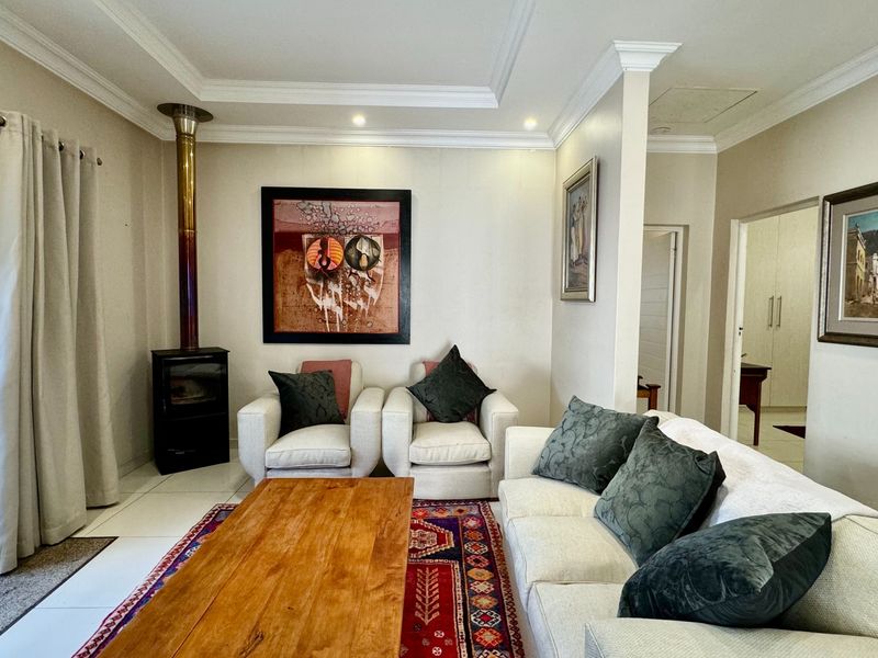 A well-maintained living room featuring tiled floors, crown molding, recessed lighting, and a cozy freestanding fireplace with direct access to the outdoor area.