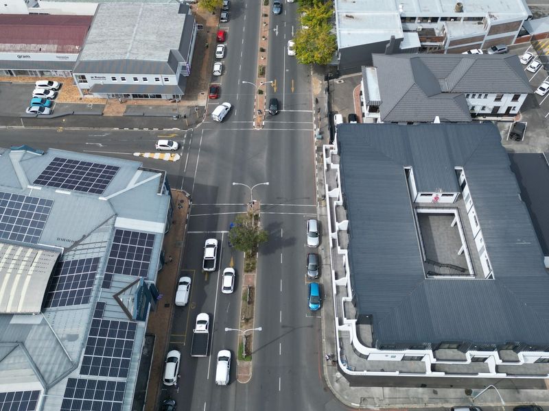 Aerial view of the property showing the building layout, roof structure with solar panels, and surrounding street infrastructure.