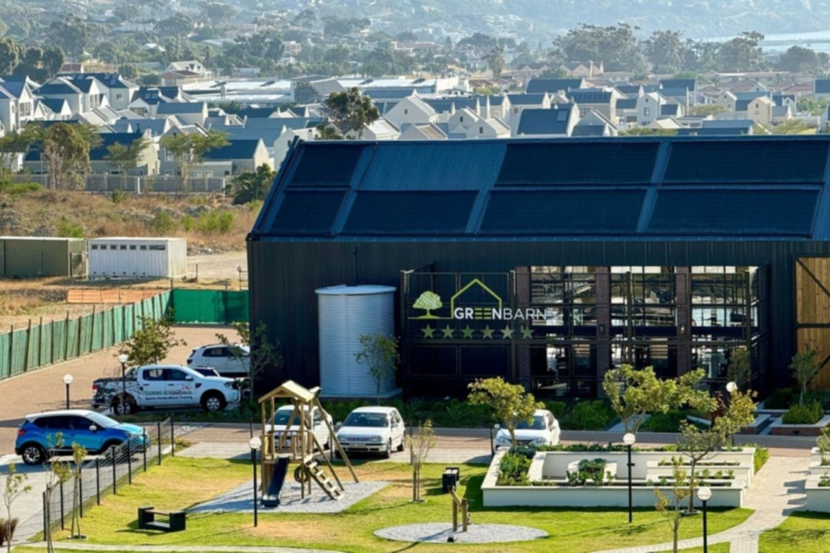 Aerial view of the Greenbarn facility featuring modern industrial architecture, solar panel roof installation, water storage tank, and landscaped grounds.