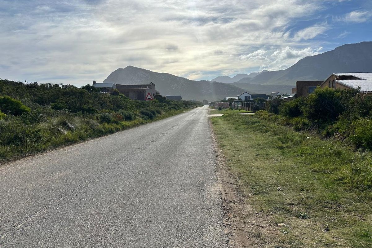 A street view showing the access road leading through a residential area with scenic mountain views in the background.