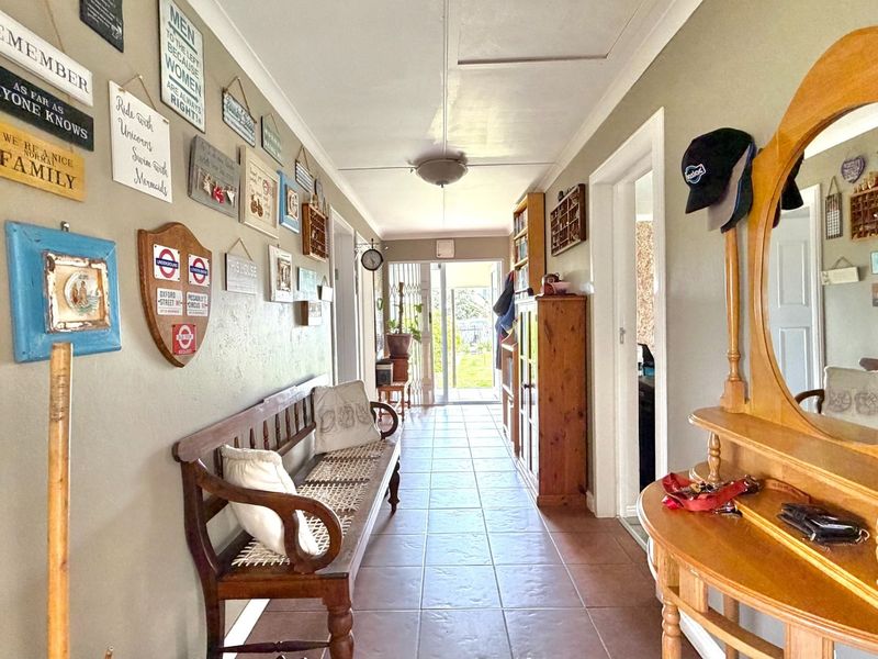 A functional hallway featuring tiled flooring and access to multiple rooms, leading towards a rear exit with natural light.
