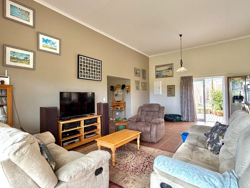 Spacious open-plan living area featuring tiled floors, high ceilings, and direct access to an outdoor patio through sliding glass doors.