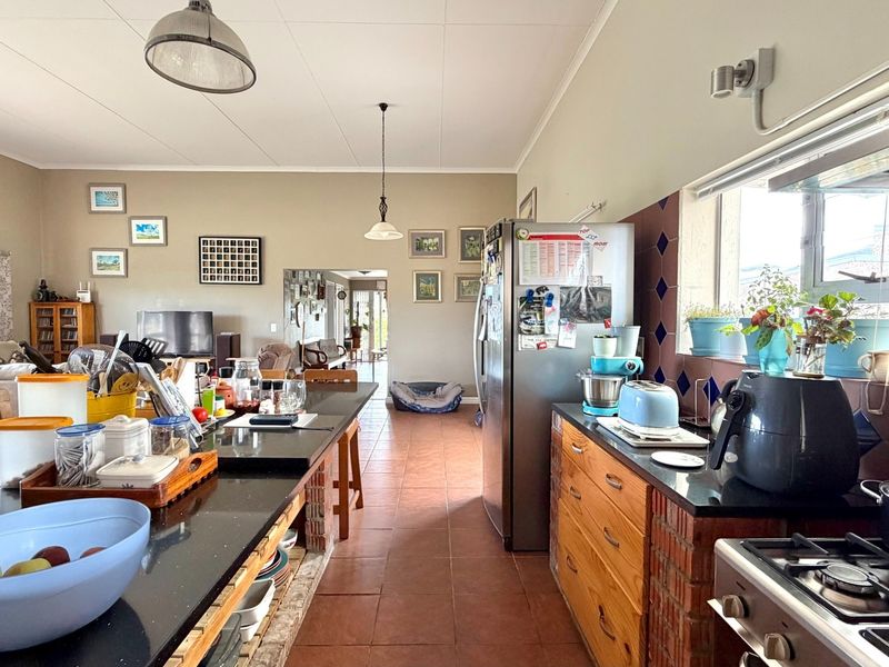 Spacious open-plan kitchen and living area featuring granite countertops, brick-based cabinetry, and tiled flooring, offering a functional layout for daily living.
