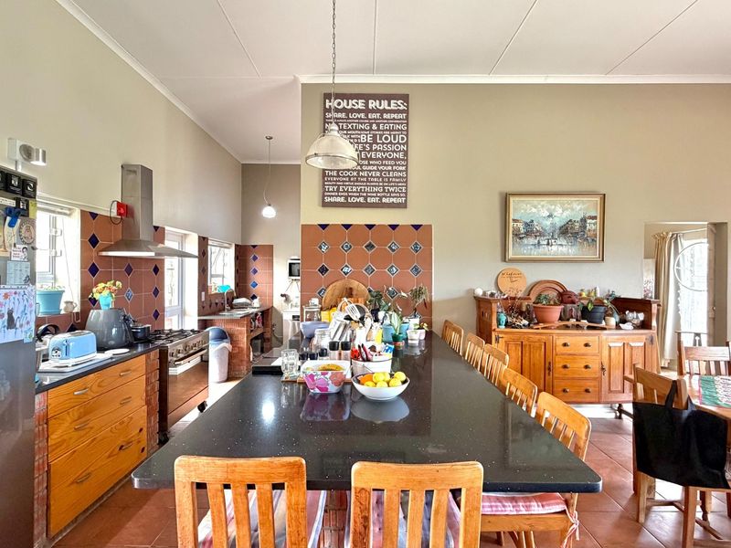 Spacious open-plan kitchen and dining area featuring a large central island with granite countertops, gas hob, and decorative tiled backsplash.
