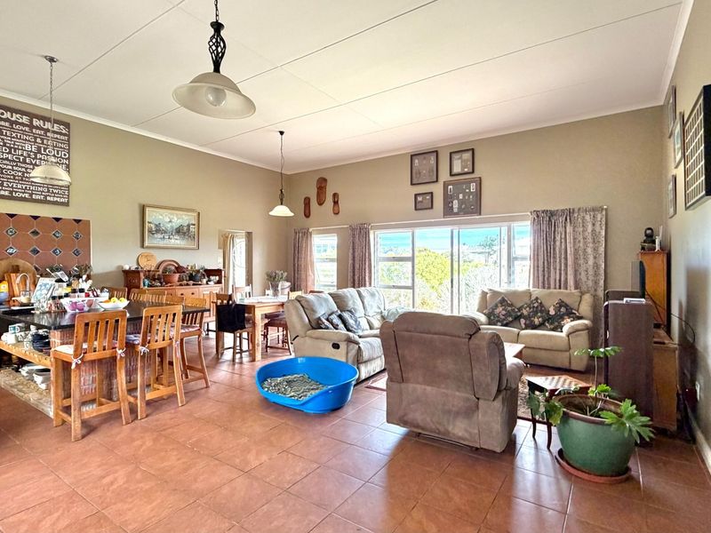 Spacious open-plan living and kitchen area featuring tiled flooring, a central kitchen island, and large sliding glass doors providing natural light.