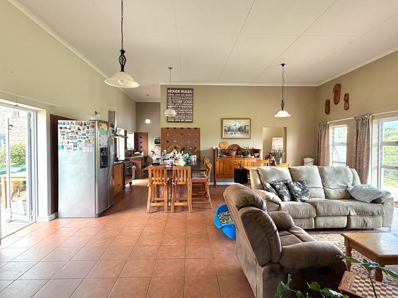 Spacious open-plan living and kitchen area featuring tiled flooring, large sliding glass doors for natural light, and functional kitchen cabinetry.