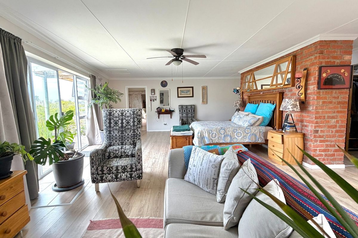 Spacious bedroom featuring laminate flooring, an exposed brick accent wall, a ceiling fan, and large sliding glass doors providing natural light and outdoor access.